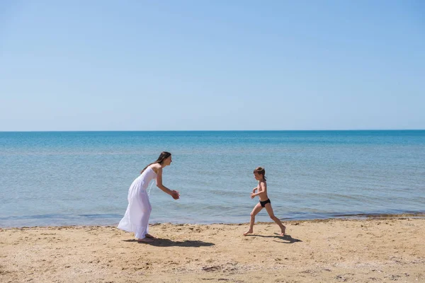 海岸で白いドレスで mom ブルネットに実行されている黒のスピード メーターの中の少年 — ストック写真