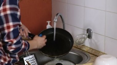 Kadın ekose gömlekli pan yıkama ve masanın üzerine koyar. Yakın çekim.