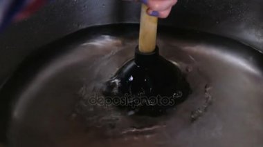 Bir mutfak lavabo ile küçük bir dalgıç prizden. Kadın bir tıkanmış lavabo temizler.