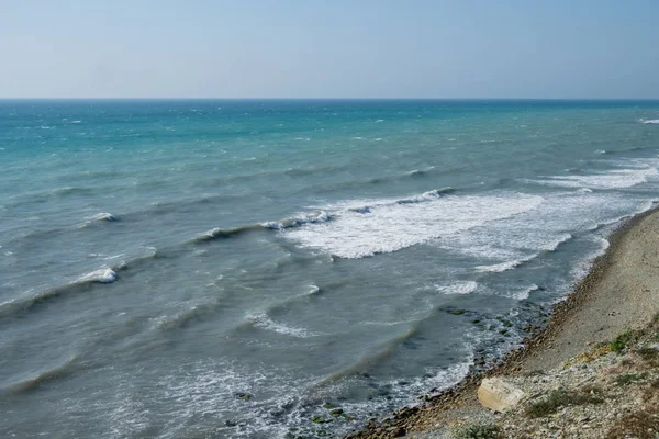 Волны катятся по морю к берегу. Каменный и песчаный пляж . — стоковое фото