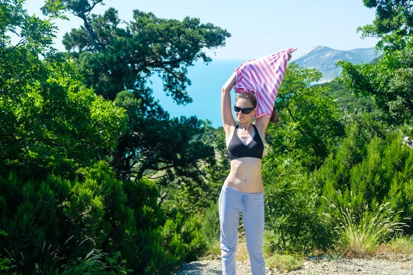 Mujer 25-30 se para en la colina con gafas de sol y quitándose la camisa . —  Fotos de Stock