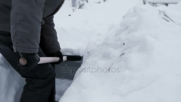 K nepoznání muž s lopatou čistí sníh bílý sníh. — Stock video