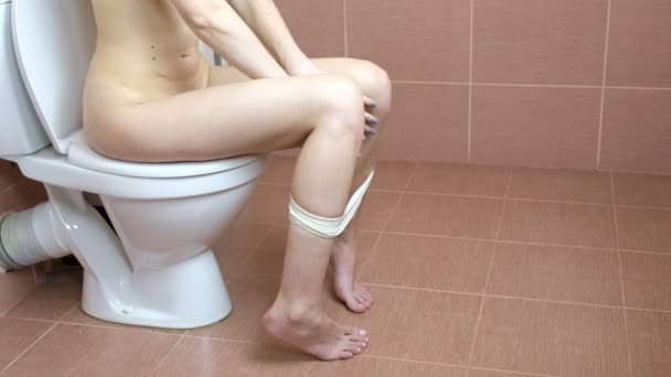 Молода жінка сидить у туалеті у ванній. 4-кілометровий — стокове відео