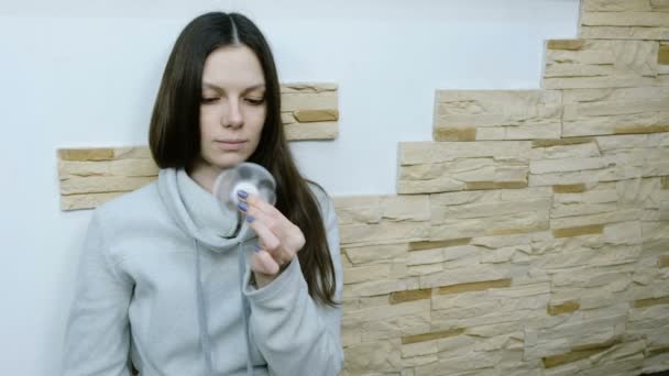 Girl fiddling with fidget spinner while sitting on the floor — Stock Video