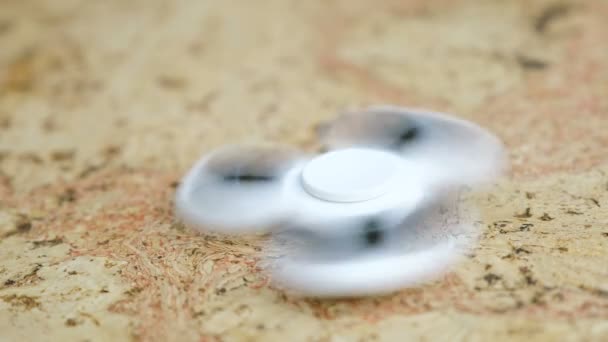 Weißer Handspinner, der sich auf einem Holztisch dreht. 4k — Stockvideo