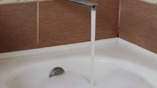 Stream of water pouring into the bath with foam. Close up. Camera movement from top to bottom. — Stock Video