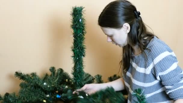 Vrouw verwijdert de onderste takken van een kunstmatige kerstboom. — Stockvideo