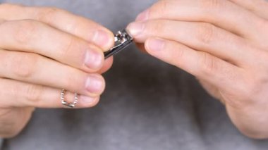 Adam onun çivi Clippers ile kesiyor. Yakın çekim parmaklar. Arka planda gri t-shirt.