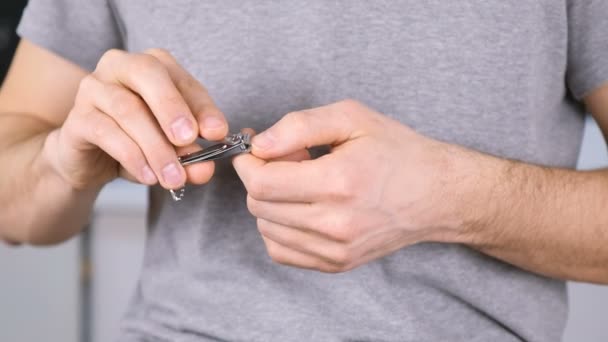 Man skär naglarna av Clippers. Närbild händer. Grå t-shirt i bakgrunden. — Stockvideo