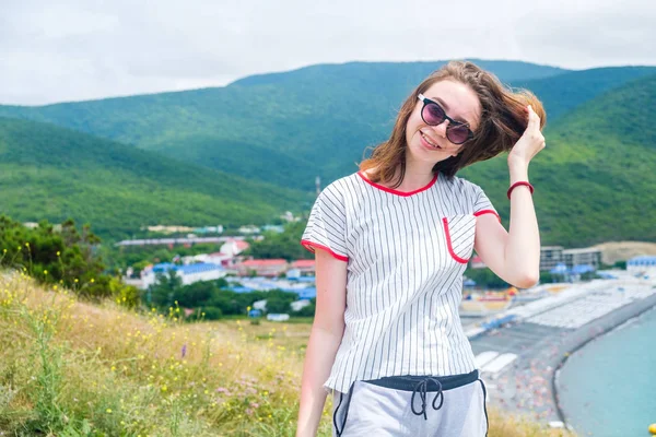 Adolescente chica 17s se encuentra en la colina en gafas de sol mirando a la cámara . — Foto de Stock