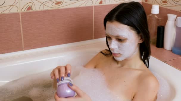 Bella donna apre un vaso con una maschera di argilla. Applicale la maschera sul viso. Bagno di casa. Home spa . — Video Stock