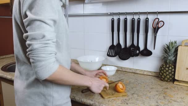 Oigenkännlig kvinna skär tomater på en skärbräda på ett köksbord. Händer på nära håll. — Stockvideo