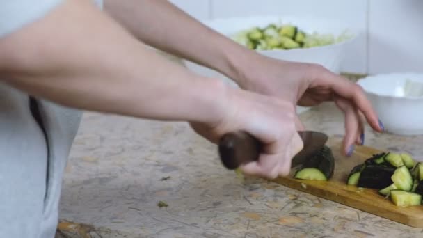 Mulher irreconhecível cortou pepino na tábua de corte na mesa da cozinha. Mãos ao alto. Vista frontal . — Vídeo de Stock