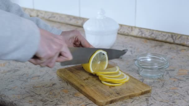 Close-up van vrouw hand snij citroen op houten snijplank in de keuken. Mes uitglijden uit citroen. — Stockvideo