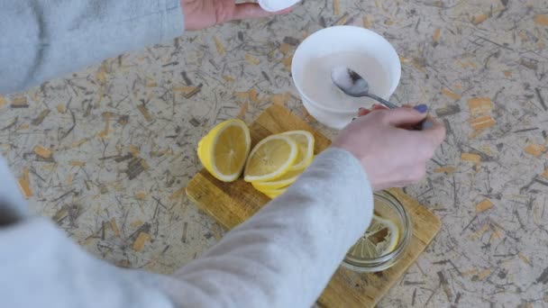 Kadın el close-up bir kavanozun içine limon dilimleri kıvrımlar ve onları bir kaşık ile şeker ile sprinkles. — Stok video