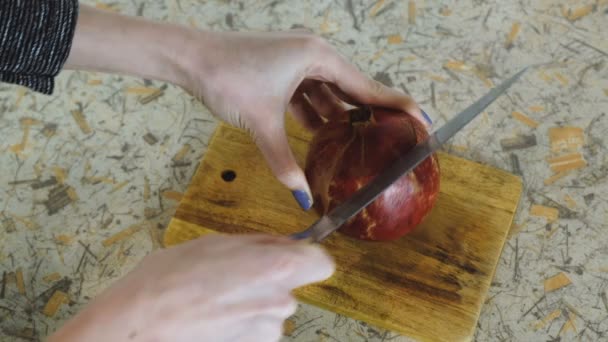 Närbild av kvinna hand skära granatäpple på skärbräda. Ljus bakgrund. Sidovy. — Stockvideo