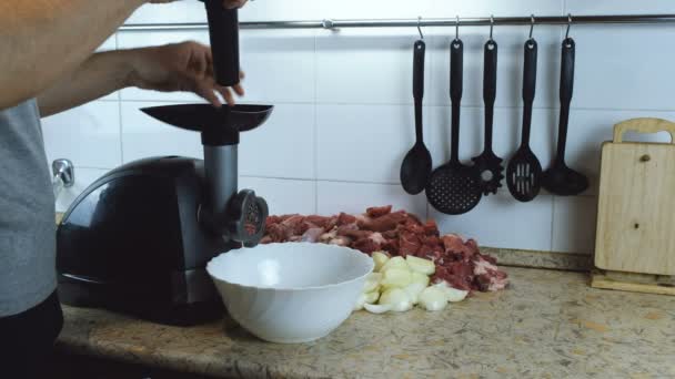 Крупним планом чоловічі руки кладуть яловичину і свинину м'ясо і цибулю через електричний м'ясоруб вдома . — стокове відео