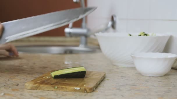 Close-up of woman hands cut cucumber on cutting board in kitchen table. Knocking knife. — Stock Video