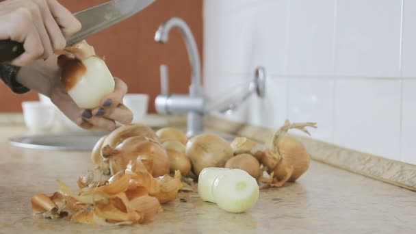 Close-up woman hands clean an onion from the husk on the kitchen table. Only hsnds. — Stock Video