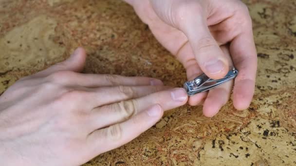 L'homme se coupe les ongles par Clippers sur la table. Doigts rapprochés. Fond en bois . — Video