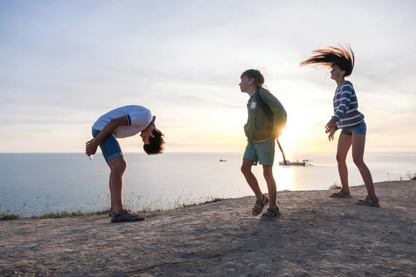 Rodzina zabawy rozrywką w górach z widokiem na morze. Tata, Mama i syn taniec o zachodzie słońca. Widok z boku. — Zdjęcie stockowe