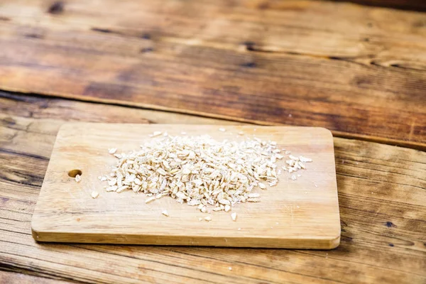 Oat flakes and grain oats in a wooden board. Farm-fresh product. — Stock Photo, Image