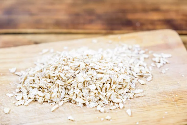 Close-up oat flakes and grain oats in a wooden board. Farm-fresh product. — Stock Photo, Image