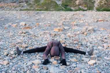 Tanınmayan kadın çakıl kıyıda uzanan. Bir ceket, tozluk ve spor ayakkabı giymiş.