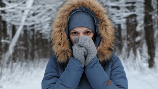 Close-up woman warms her hands in the cold with her breath in winter forest. — Stock Video
