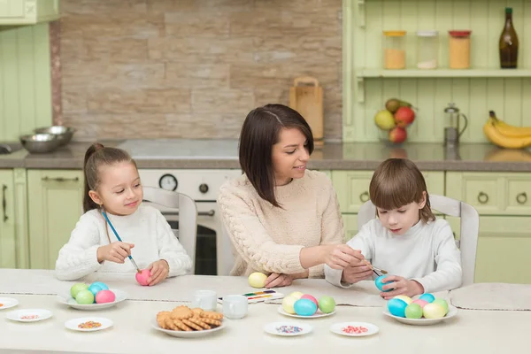 Szczęśliwa matka i dziecko malować pisanek na stole w kuchni — Zdjęcie stockowe