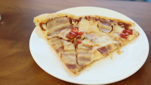 Primer plano de rebanada de pizza con tocino y pimiento dulce en plato blanco en mesa de madera . — Vídeos de Stock