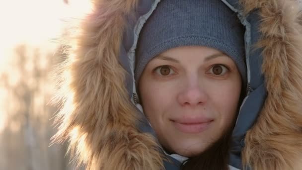 Close-up vrouw gezicht bont Hood in de camera kijken en glimlachend in de winter. Recht op video. — Stockvideo