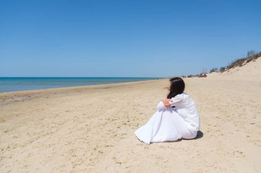 Genç kadın uzak denizde kıyıya otururken arıyor