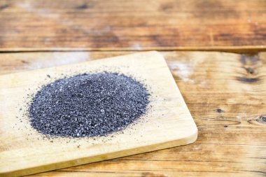 Siyah ahşap tahta üzerinde tuz. Ahşap arka plan. Fotoğraf solda. Yan görünüm.