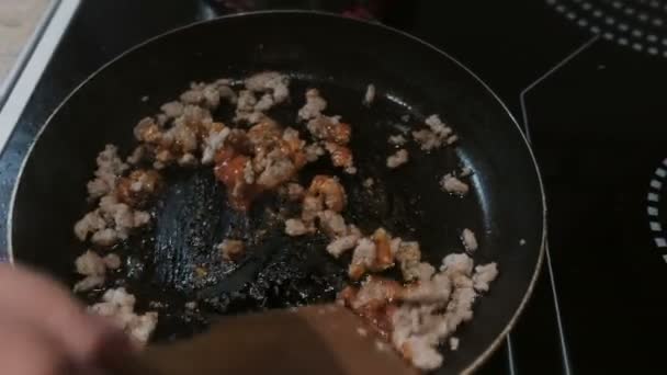 Mescolare con una pala di legno di arrosto carne macinata con salsa di pomodoro in una padella . — Video Stock