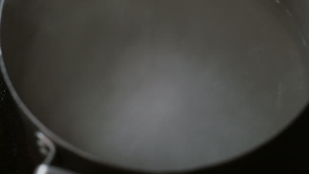 Oskärpa bakgrund närbild kokande vatten i en kastrull på spisen. — Stockvideo