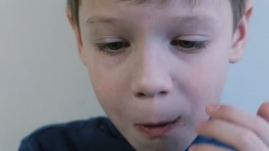 Yakın çekim yüz waffle ısırma ve çiğneme onları bir 7years çocuk. Kırıntıları sinek her yöne.