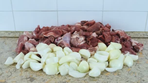 Trozos de cerdo y carne de res y cebollas en la mesa de la cocina. Cámara de movimiento de arriba a abajo . — Vídeos de Stock