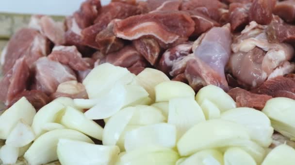 Close-up view pieces of meat beef and pork and many onions. Camera move from left to right — Stock Video