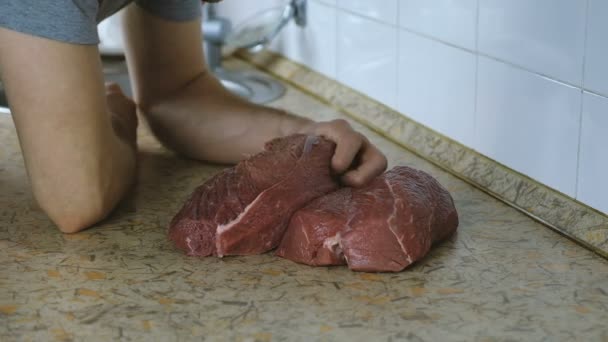 Man bites off a piece of raw beef and chews it. Eskimo is eating uncooked beef meat. Slow motion — Stock Video