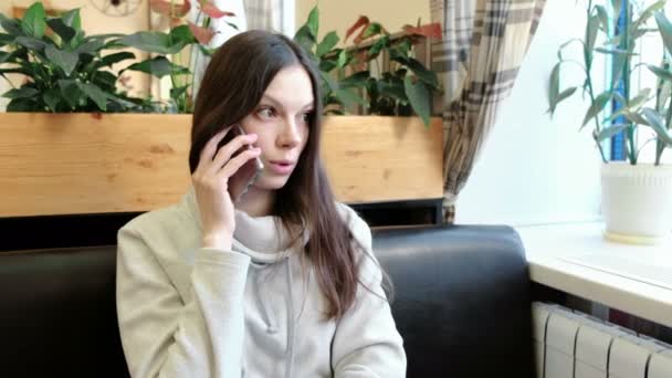 Belle femme brune parlant son téléphone portable dans un café, semble grave et bouleversé . — Video