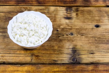 Ev yapımı peynir ahşap arka plan üzerinde beyaz tabakta. Üstten Görünüm. Plaka üzerinde fotoğraf solda.