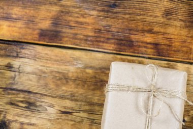 Yakın çekim yarım hediye kraft Kağıt ahşap arka plan üzerinde sarılı. Fotoğraf solda.