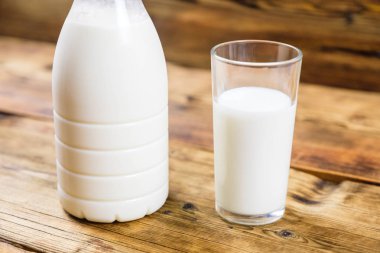 Taze çiftlik süt ve süt ahşap arka plan üzerinde yakın çekim şişe.