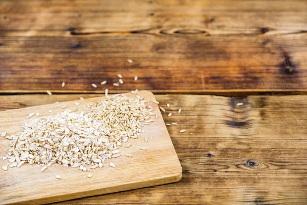 Close-up oat flakes and grain oats in a wooden board. Farm-fresh product. On the left of the photo. — Stock Photo, Image