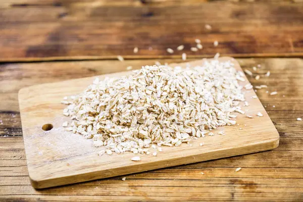 Close-up oat flakes in a wooden board. Farm-fresh product. Top view. — Stock Photo, Image