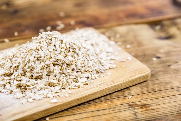 Close-up bunch oat flakes in a wooden board. Farm-fresh product. Side view. — Stock Photo, Image