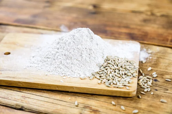 Close-up heap with wheat flour coarse and grain on a wooden board. — Stock Photo, Image