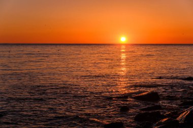 Denizde, güneş ufuk da yüksek olduğunda güzel gün batımı.