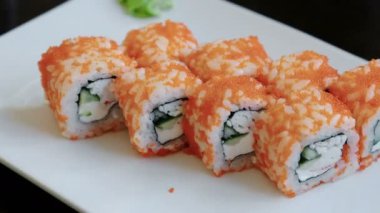 Yakın çekim havyar ile turşu zencefil ve wasabi ile beyaz dikdörtgen plaka üzerinde rulo. Kamera Döndür.